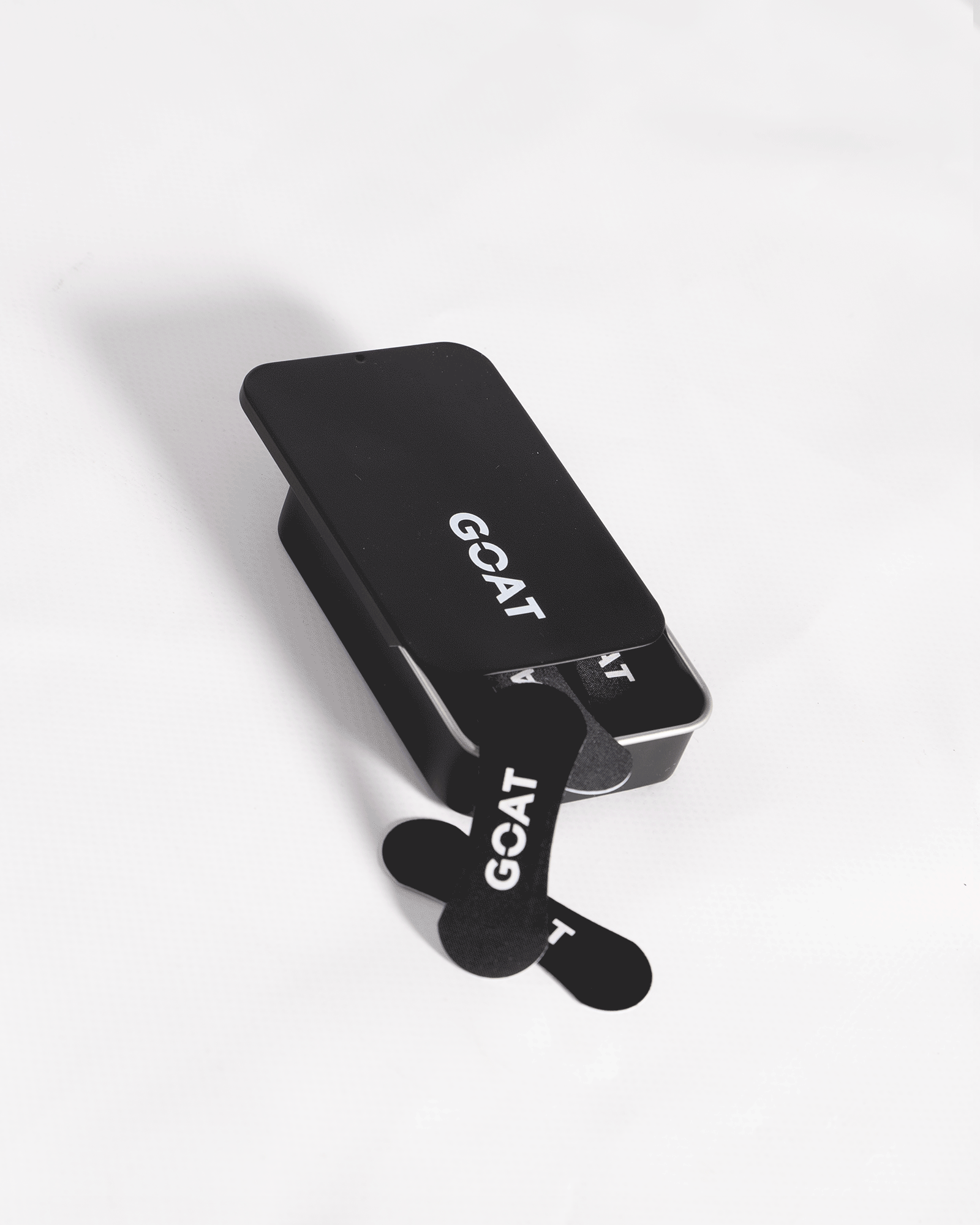 Black GOAT-branded metal case with crossed black patches.