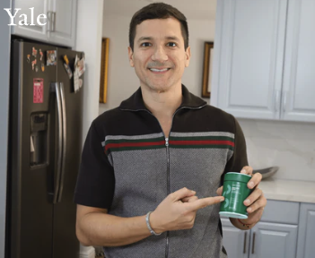 Person smiling and pointing at a green can in a kitchen.