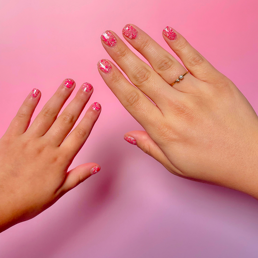 Two pairs of hands, likely an adult and child, with matching pink glitter nail polish.