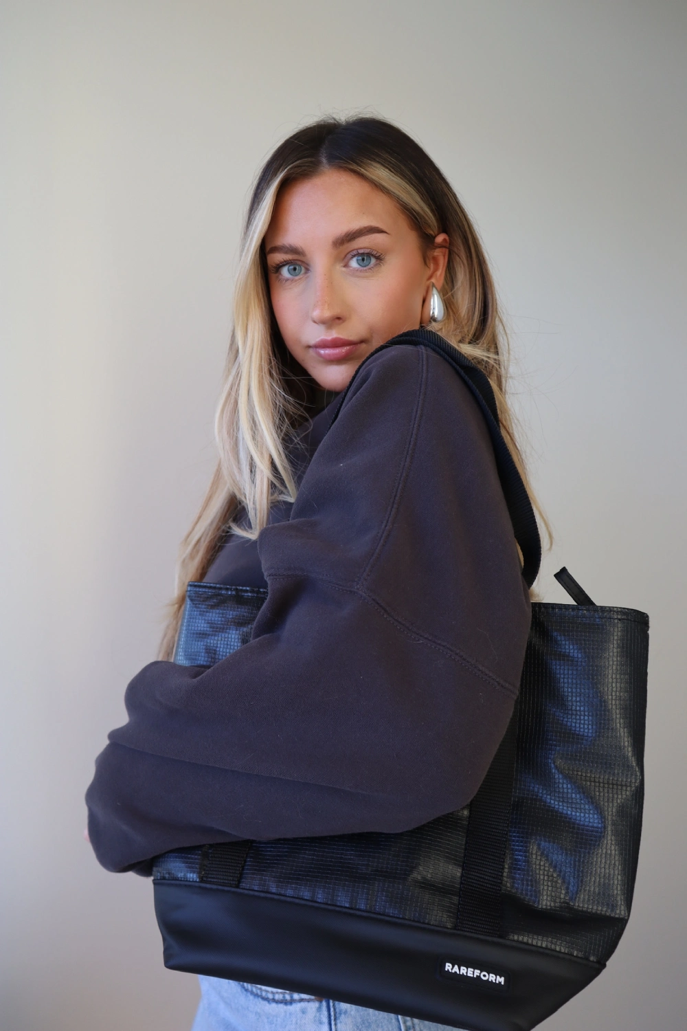 Person with long hair holding a black tote bag.