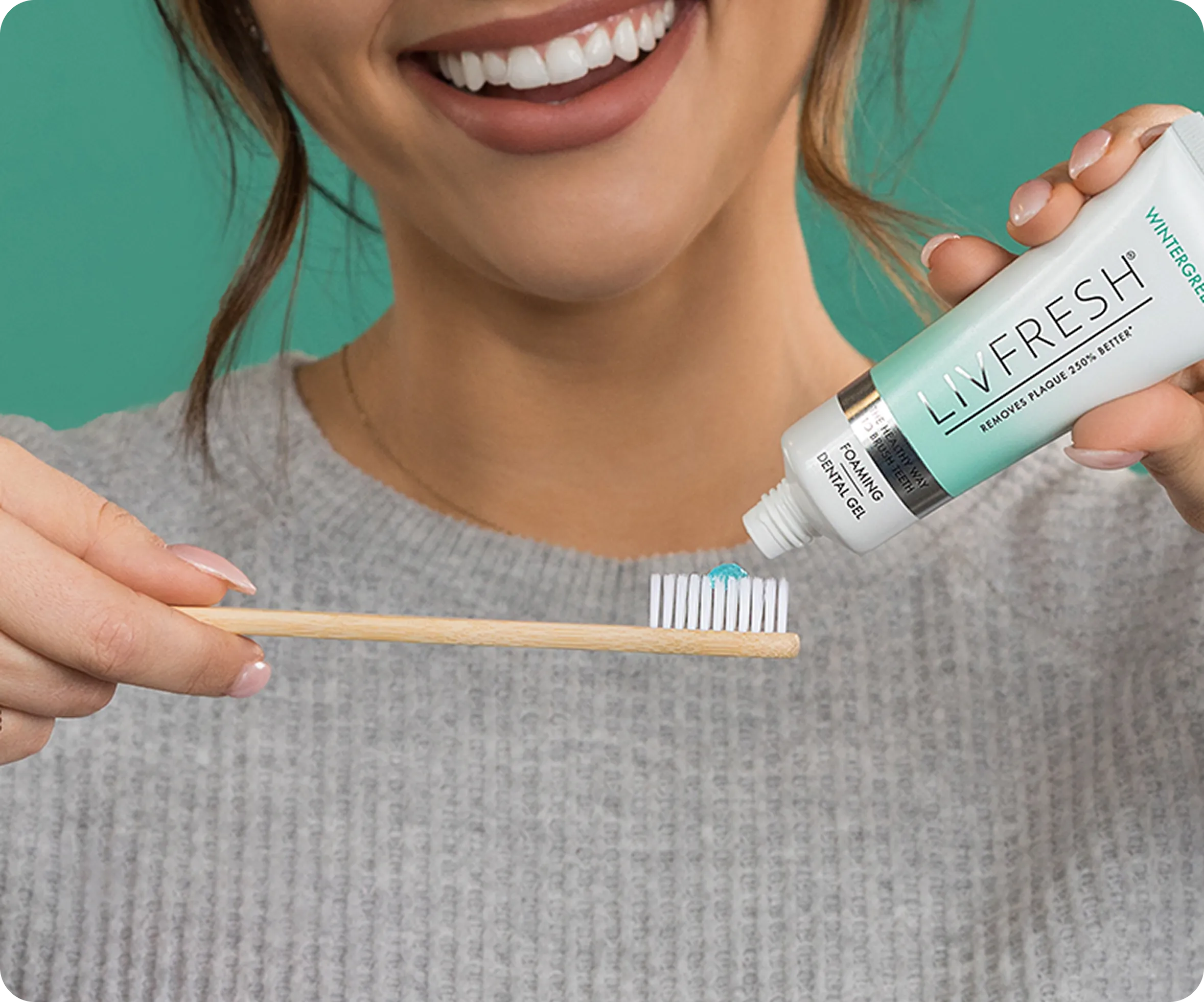 Person applying toothpaste to a toothbrush, smiling.