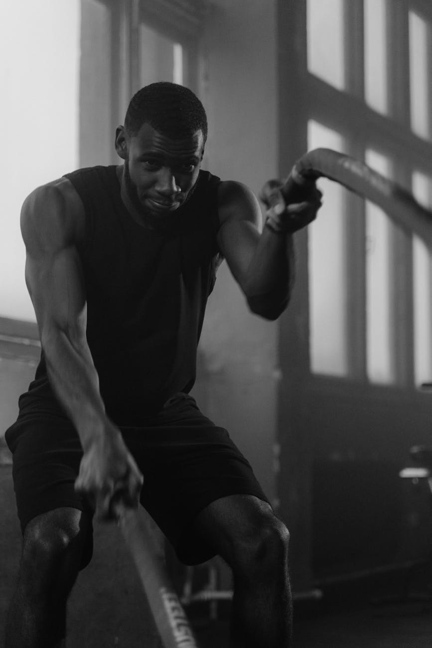 Man exercising with battle ropes in a gym.