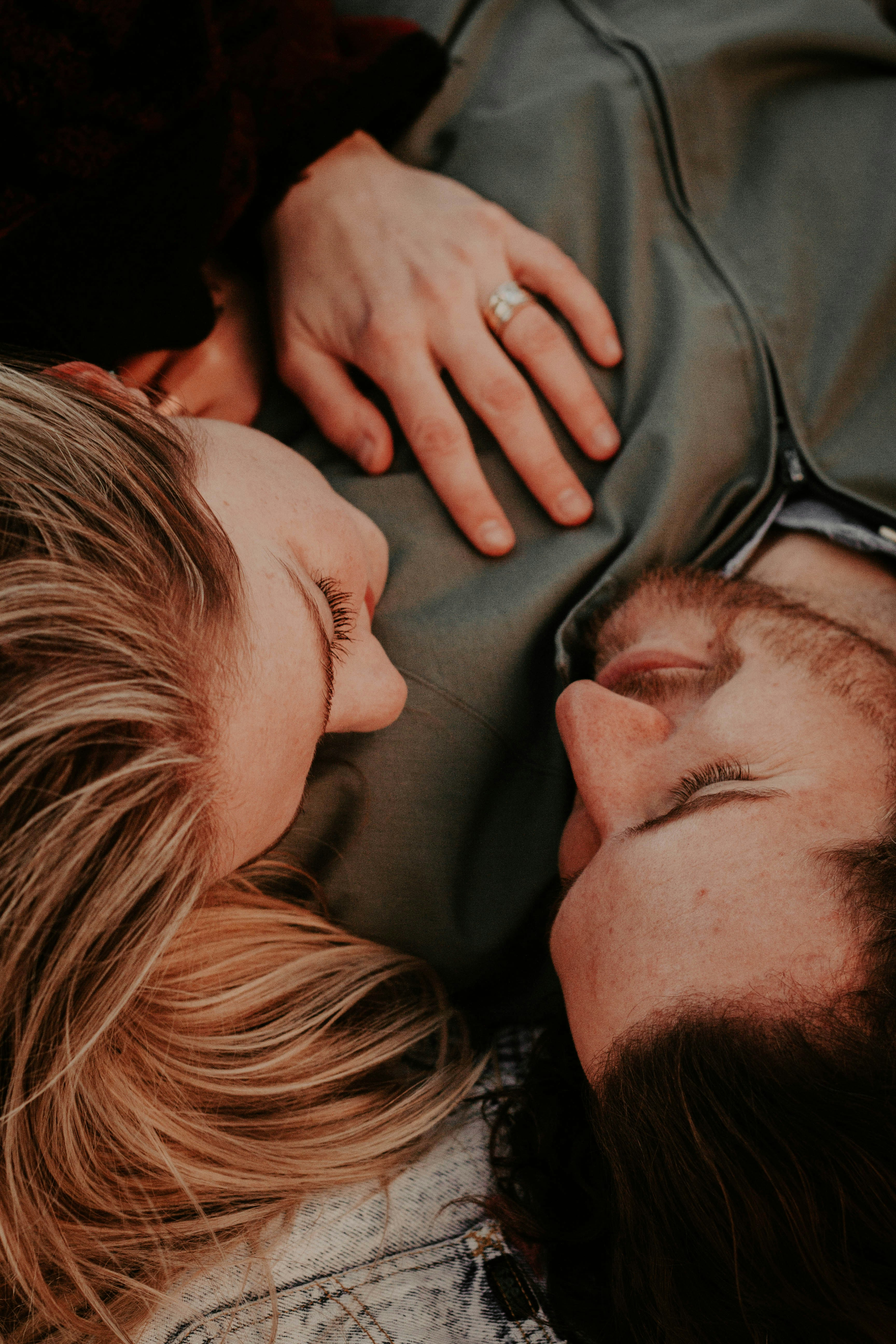 Two people lying close together, one with a hand on the other's chest.