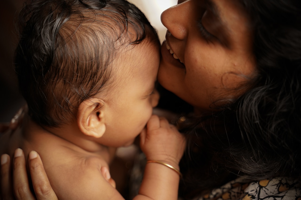 A woman smiling at a baby she is holding.