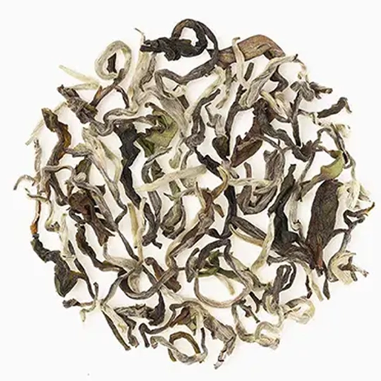 A circular pile of loose, twisted, dried tea leaves on a white background.
