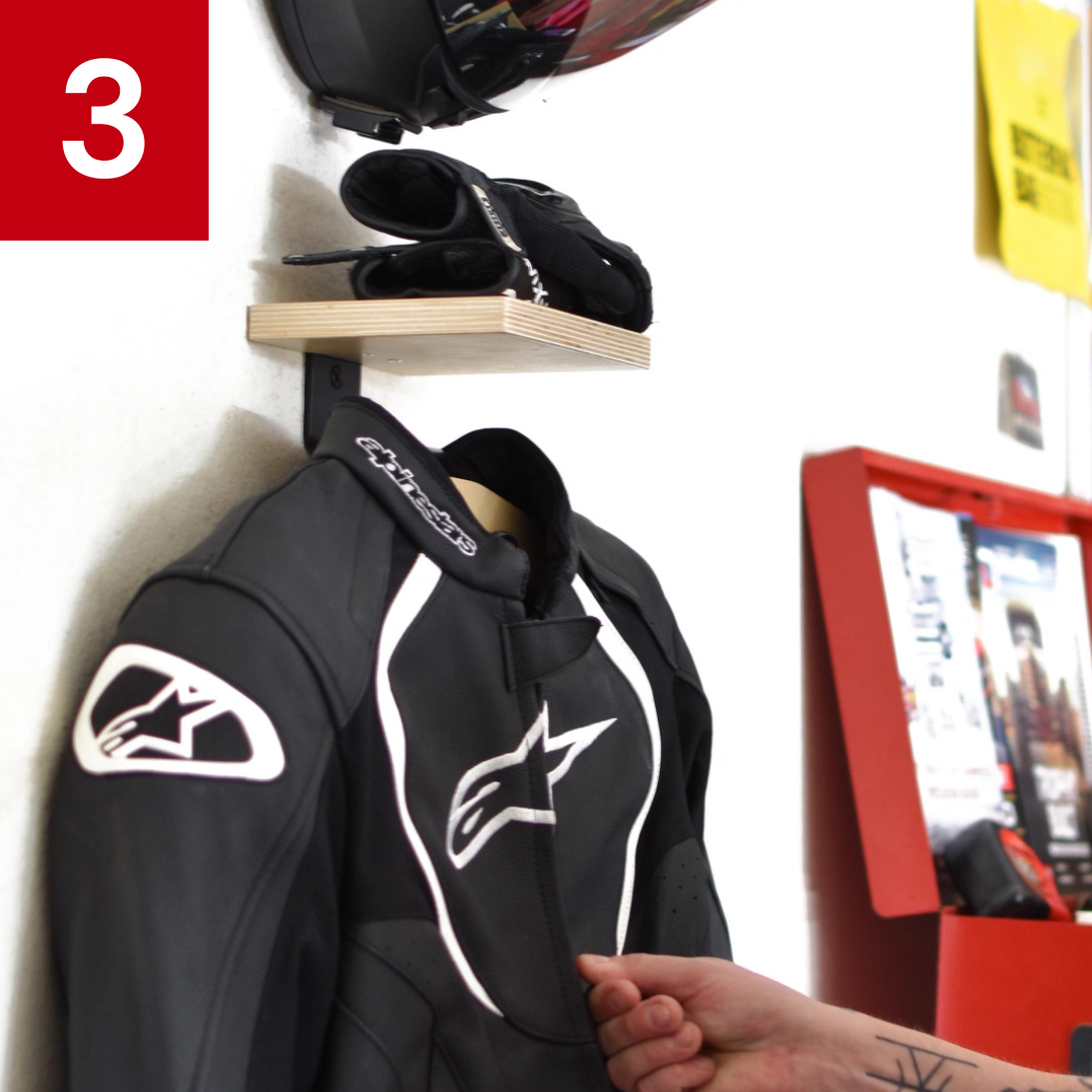 Motorcycle gear setup with jacket, gloves, and helmet on wall.