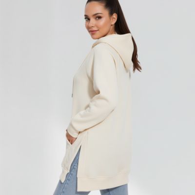 Person wearing a cream hoodie and jeans, looking over shoulder.