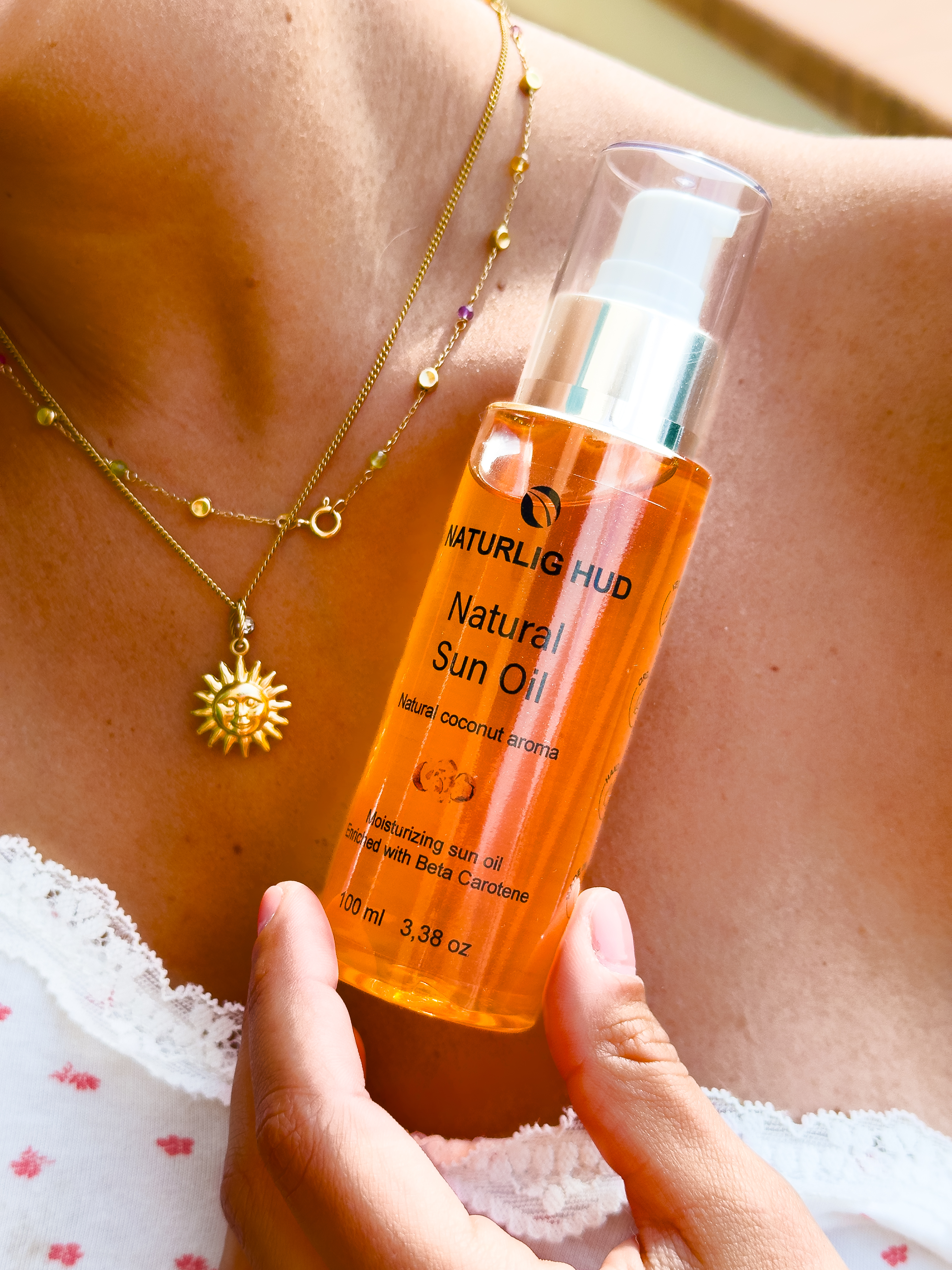 Person holding a bottle of natural sun oil near their neck.