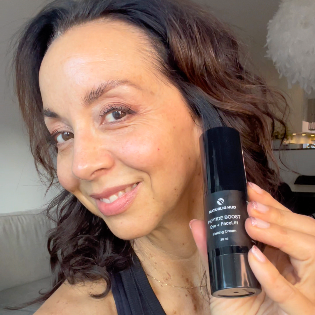 Person smiling and holding a bottle of skincare product.