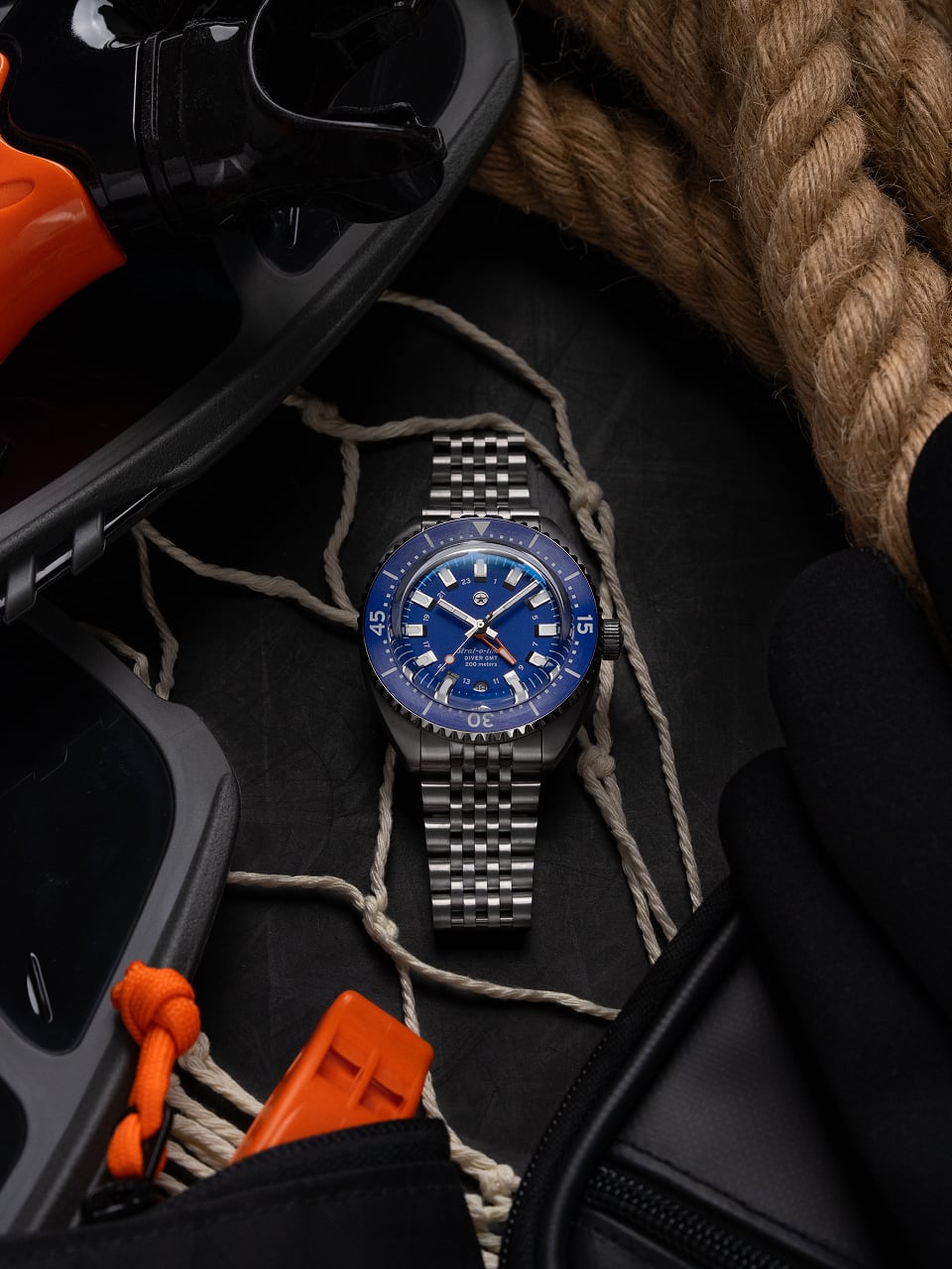 Silver and blue wristwatch surrounded by rope and diving equipment.