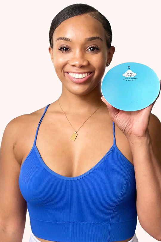 Smiling woman holding blue Honey Cloudz oval bra insert for superior shaping, coverage, and secure all-day fit in sports bras and swimwear.