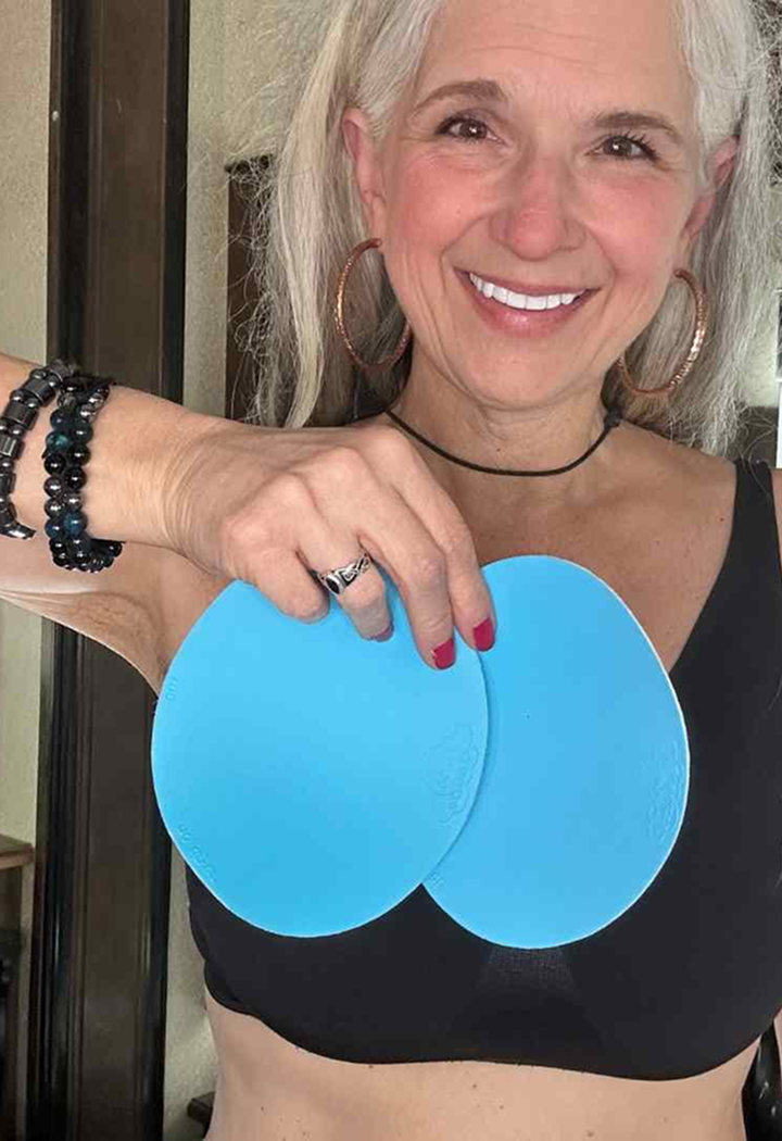 Smiling woman holding two blue circular objects in front of her chest.