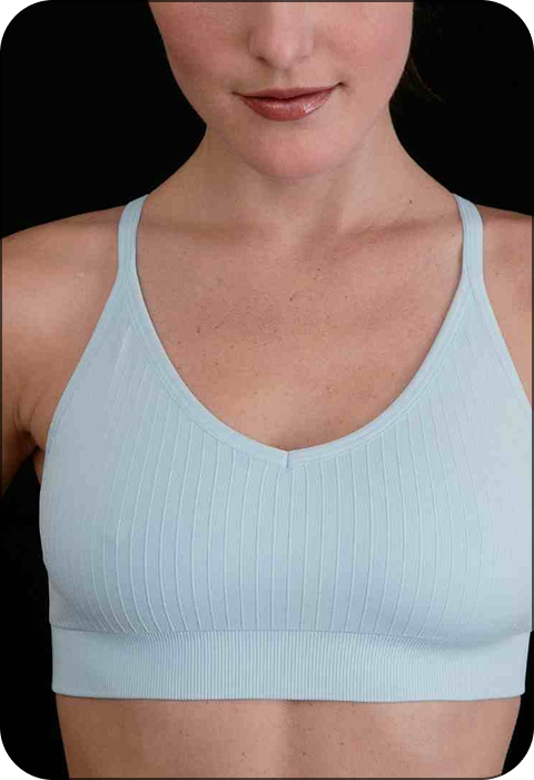 Person wearing a light blue ribbed sports bra against a black background.