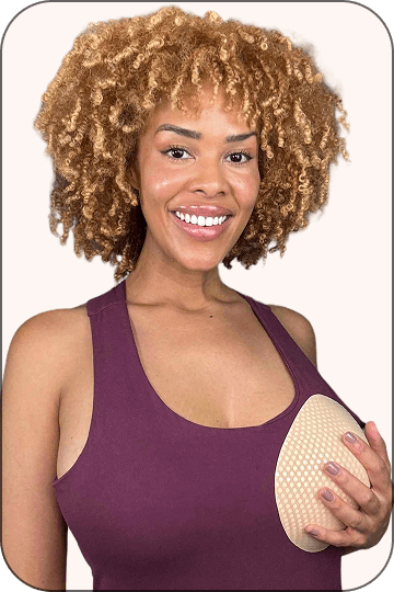 Woman with curly hair holding a skin-tone pad on her chest.