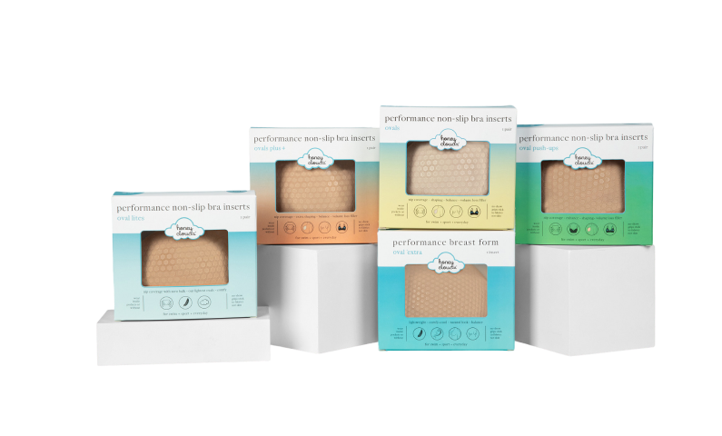 Five boxes of performance non-slip bra inserts on white stands.