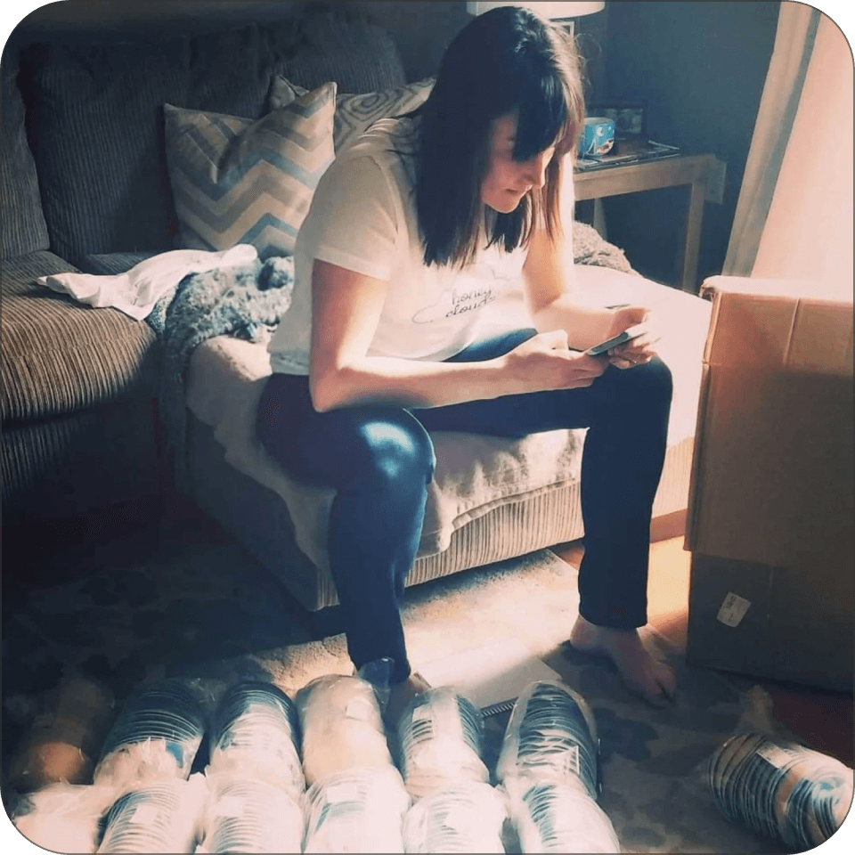 Person sitting on a chair, holding a smartphone, with yarn skeins on the floor.