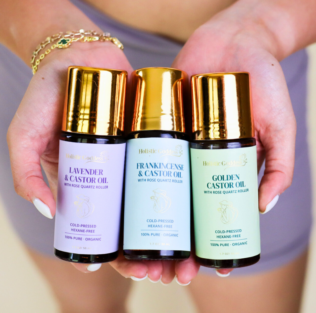 Three bottles of essential oils with gold caps held in hands.