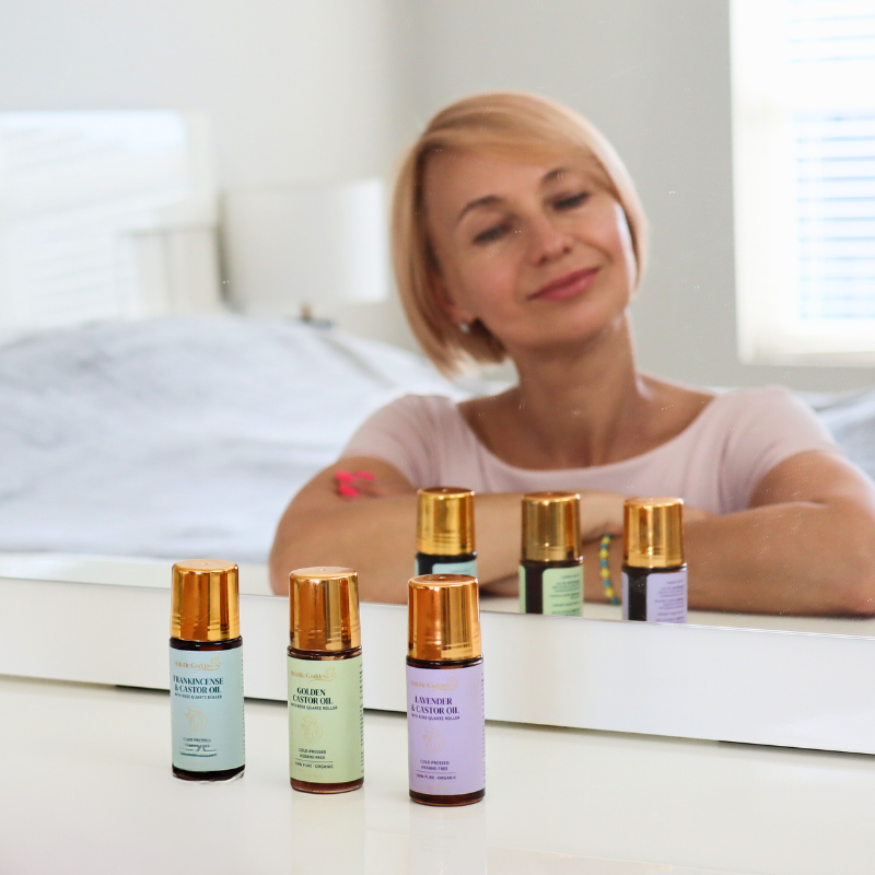 Woman smiling in mirror with essential oil bottles on dresser.