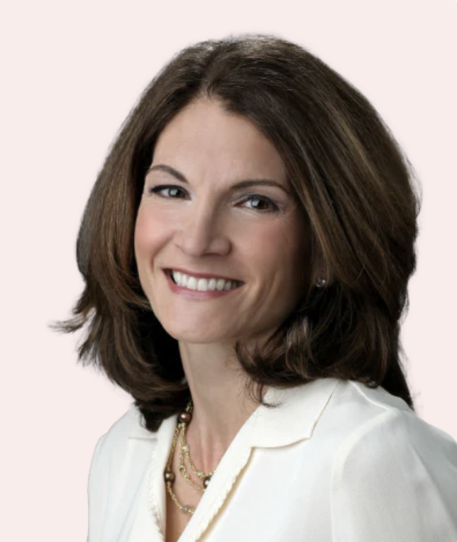 Smiling woman with shoulder-length brown hair in a white blouse.