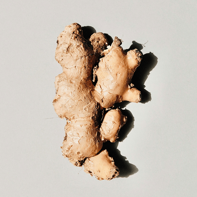 A piece of fresh ginger root on a light background.