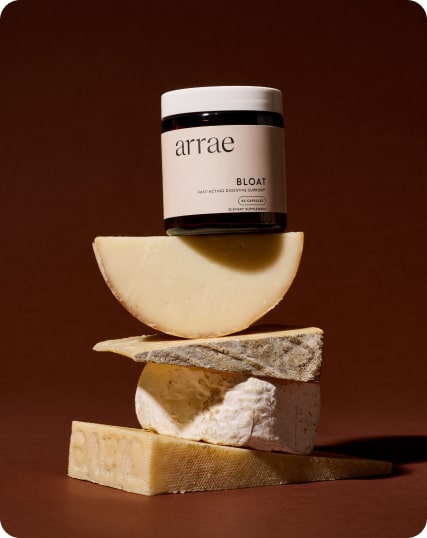 Jar labeled 'arrae Bloat' on stacked cheese pieces against brown background.