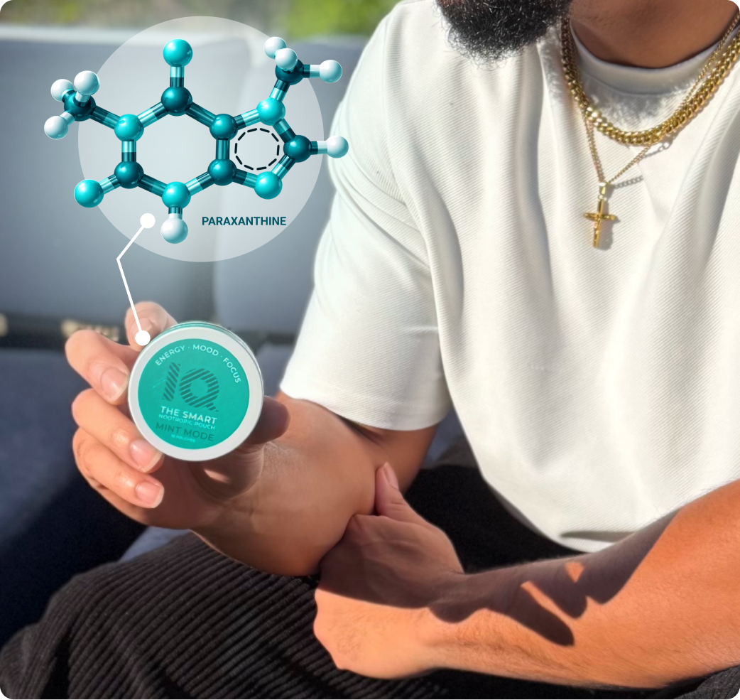 A man holds a small, round container with a graphic of a paraxanthine molecule pointing to it.