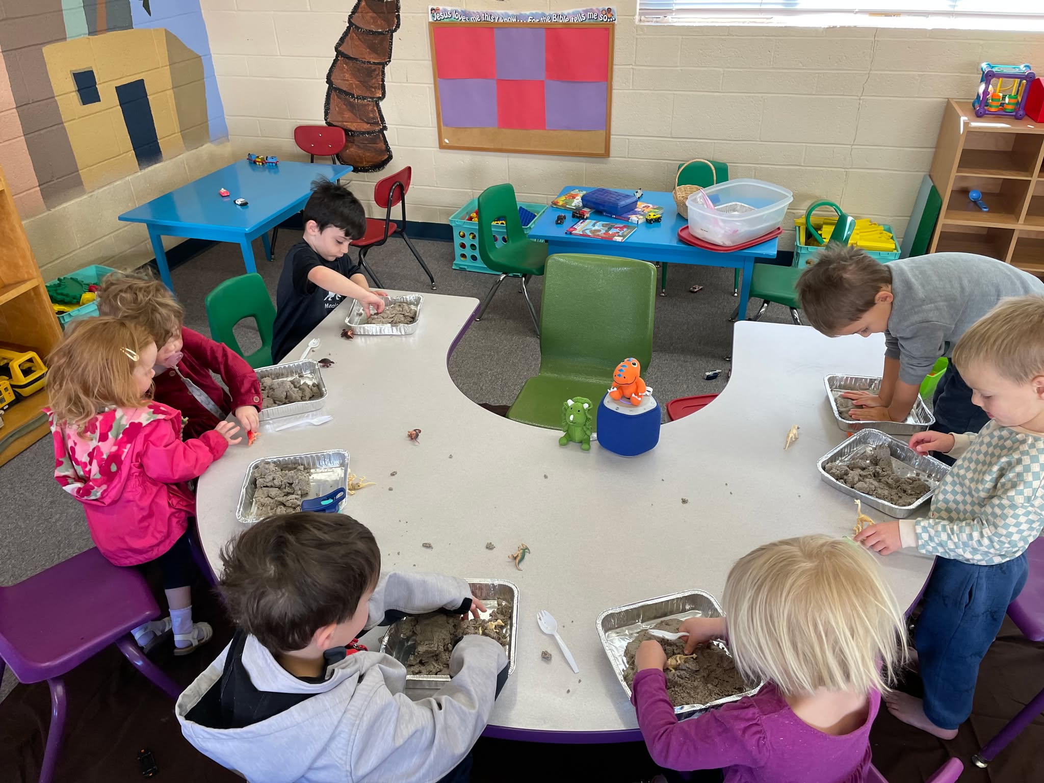 Children playing with clay at a classroom table.