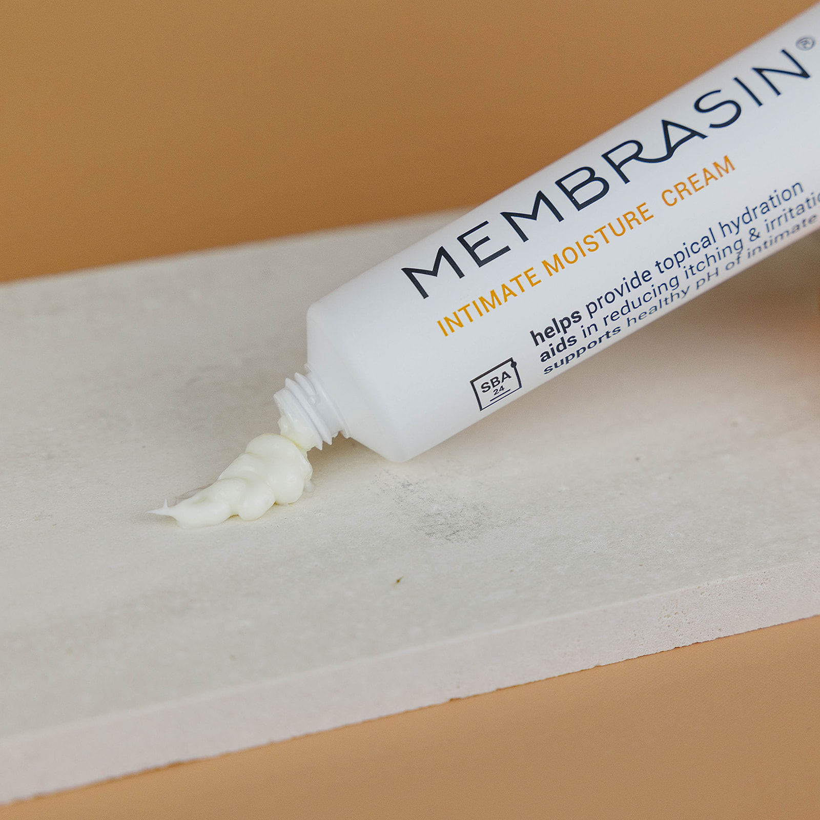 A tube of Membrasin Intimate Moisture Cream with some cream squeezed out onto a textured, light-colored surface.