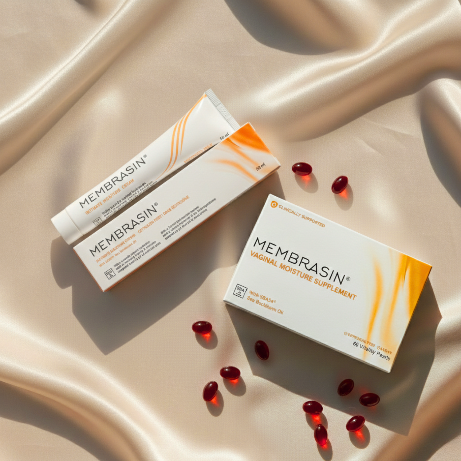 Membrasin intimate moisture cream and vaginal moisture supplement products arranged on a silky champagne-colored fabric.