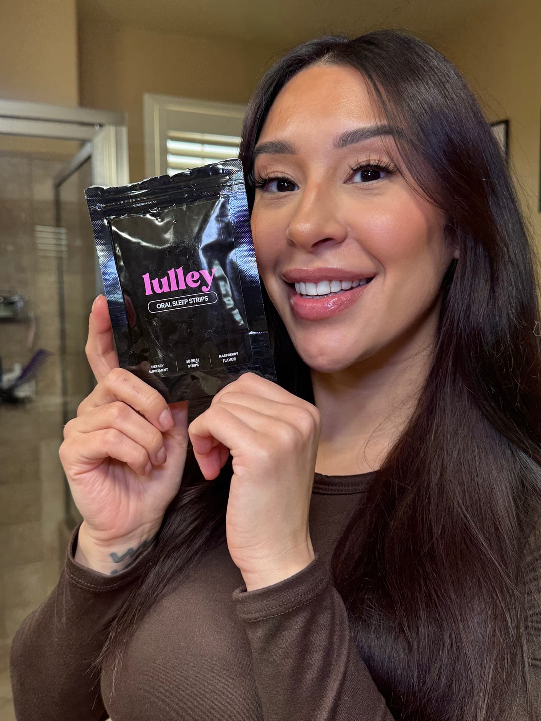 Person holding a packet of oral sleep strips and smiling.