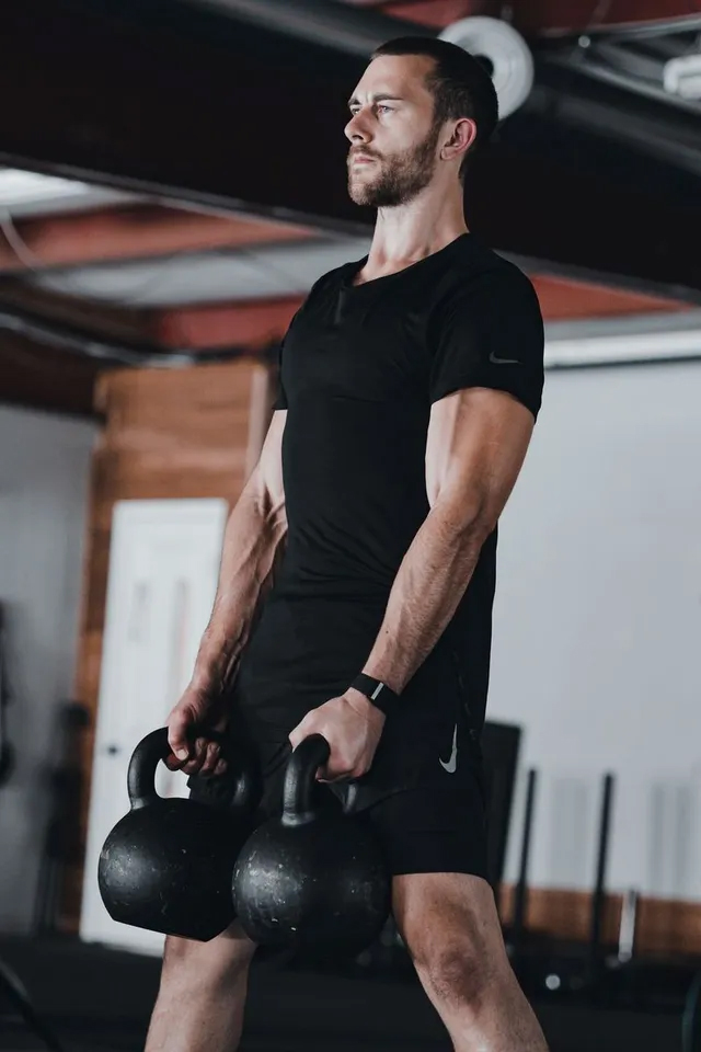 Four women in athletic attire run together on a gravel path through a wooded area.