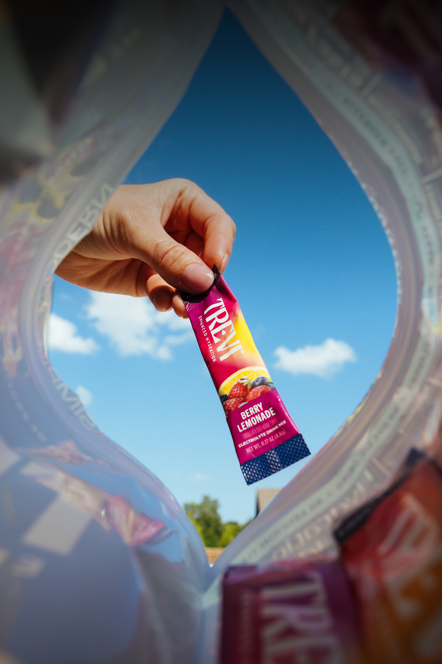 A unique perspective from inside a bag, looking up at a hand holding a berry lemonade drink mix packet.