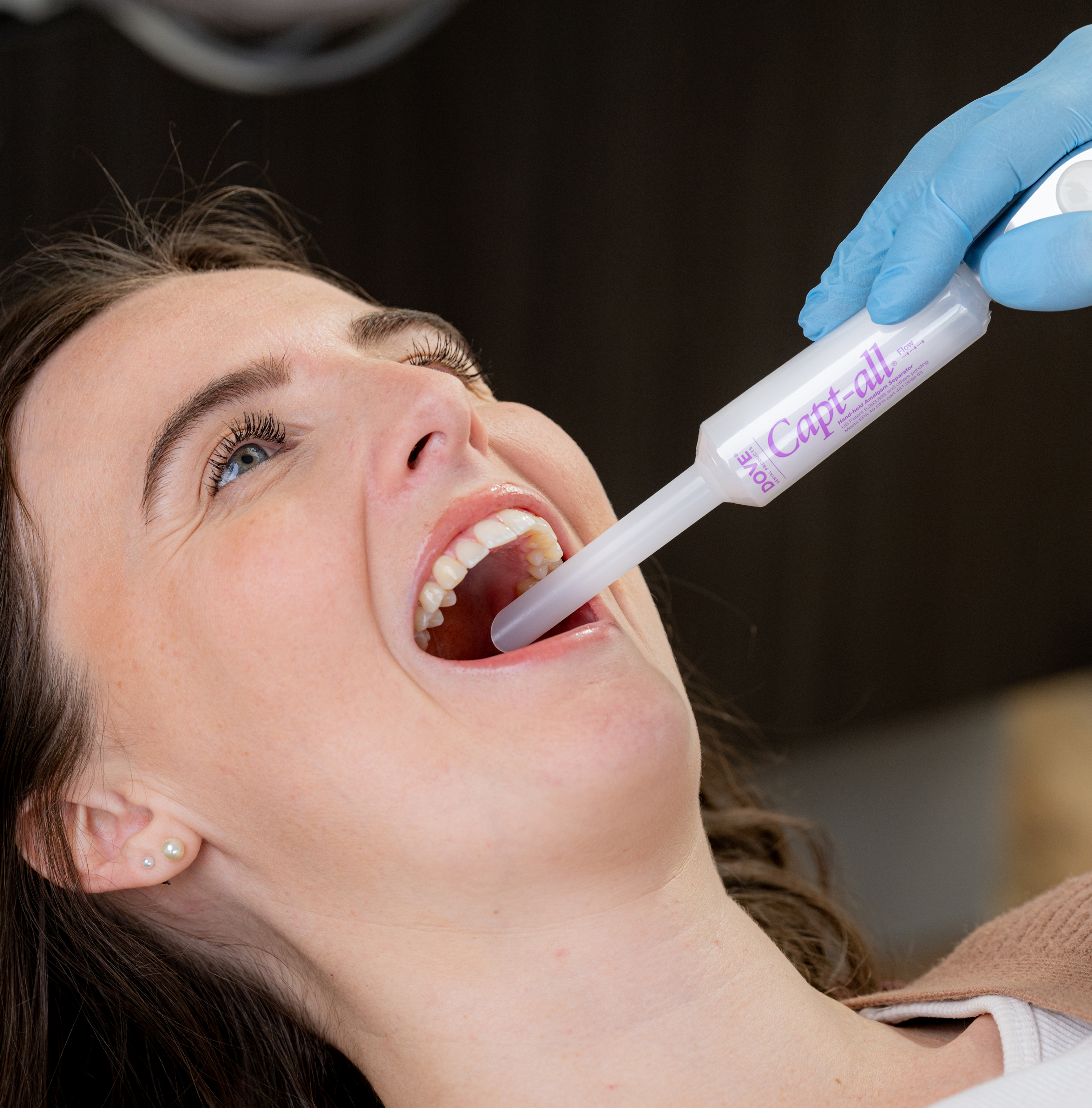 Person receiving dental treatment with a syringe tool in their mouth.