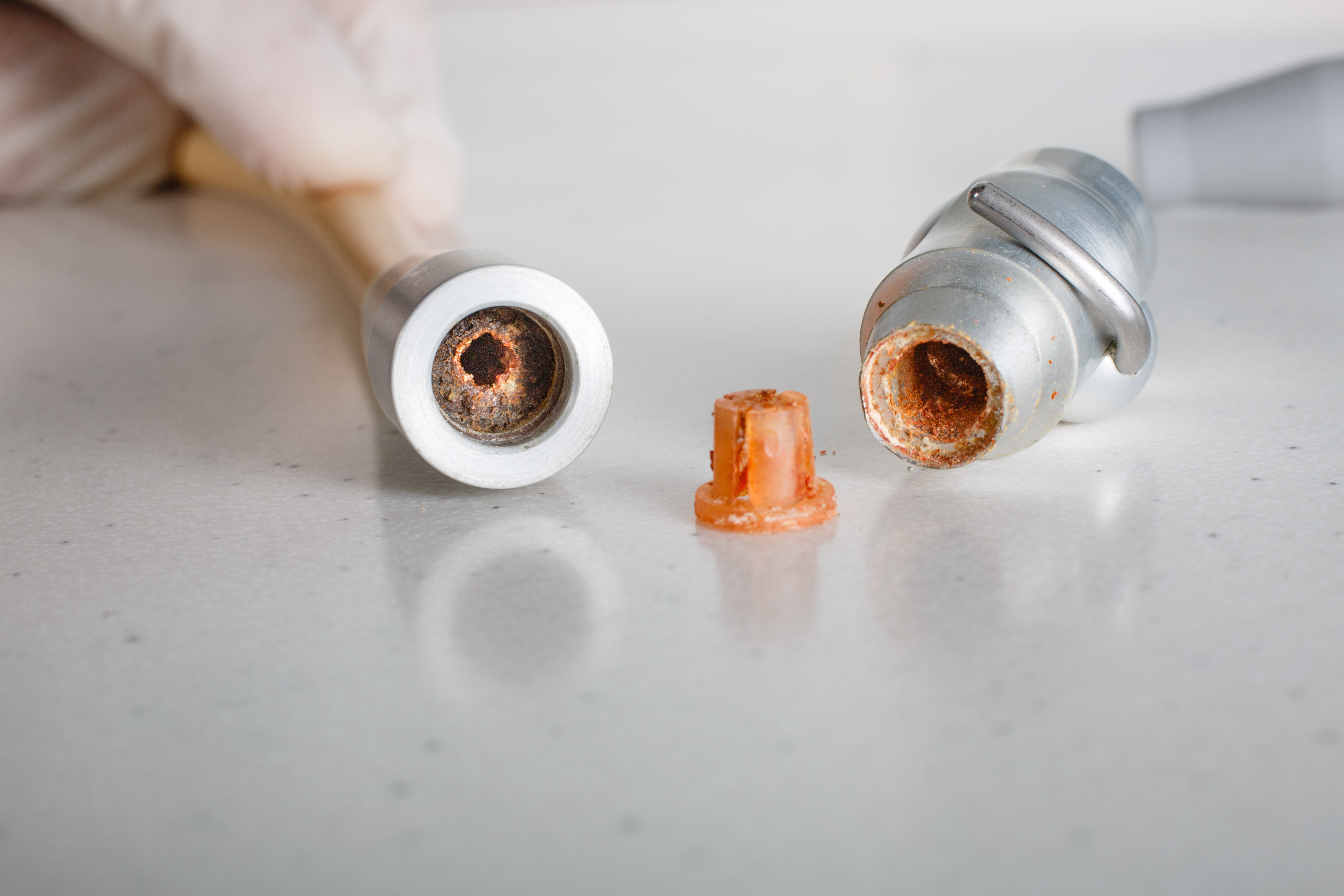 Close-up of two corroded metal pipes with a small rusted piece between them.