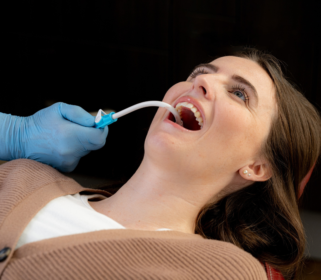 Person receiving dental treatment with a suction tool in their mouth.