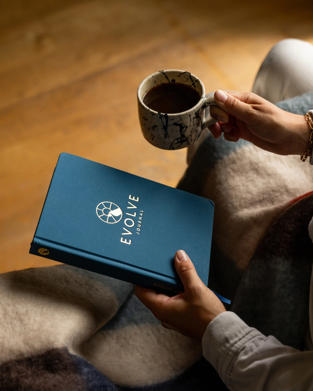 Person holding a blue journal and a mug of coffee.