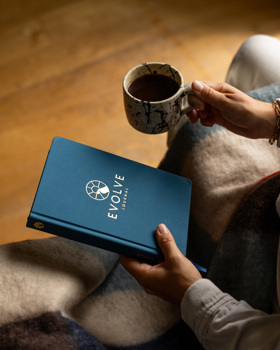 Person holding a blue journal and a mug of coffee.