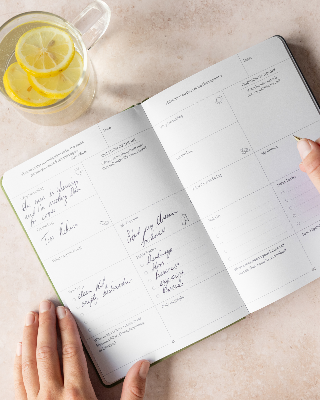Open planner with handwritten notes, next to a mug of lemon water.