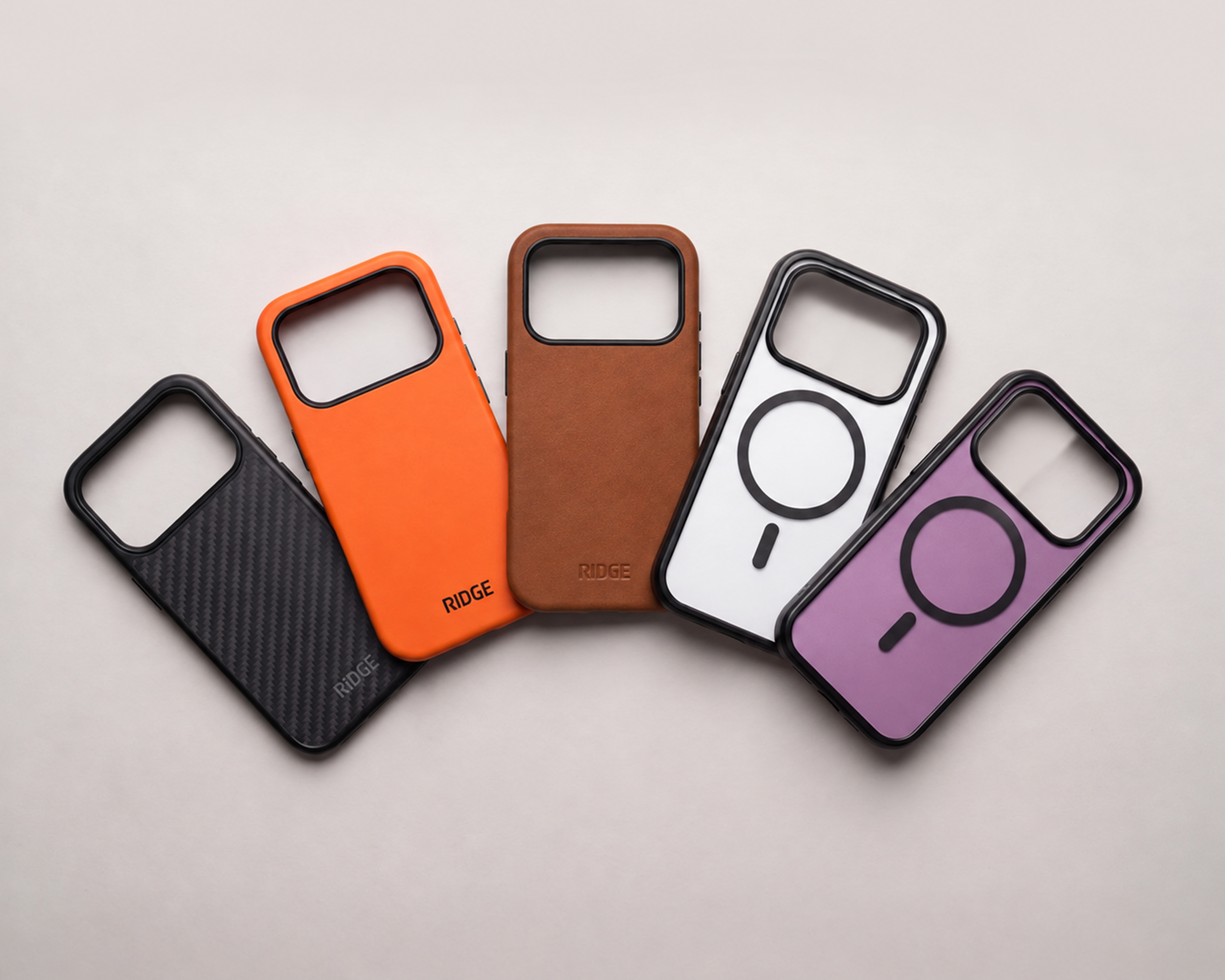 An overhead shot of five colorful Ridge brand phone cases fanned out on a light surface.