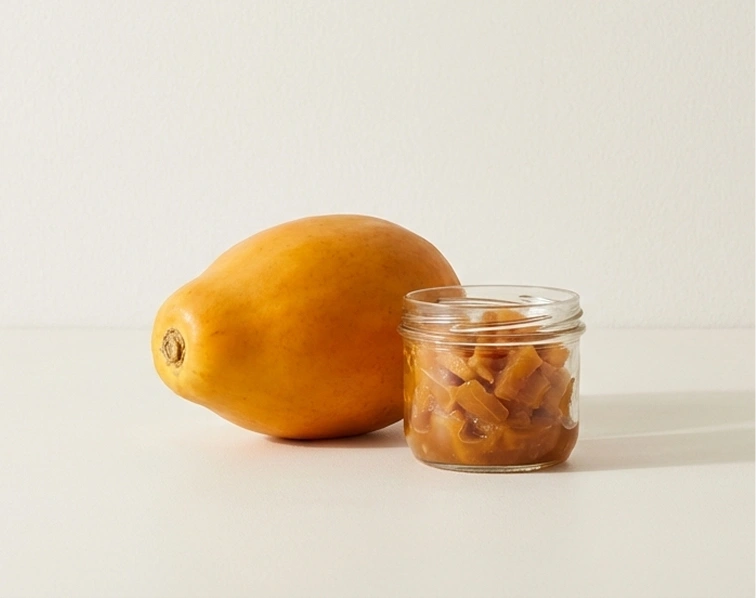 A whole yellow fruit beside a jar of diced fruit pieces.