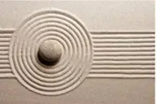 A zen garden with a single stone and sand raked into concentric circles and straight lines.