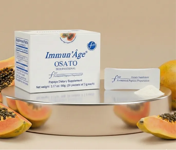 A box and packet of Immun'Âge Papaya Dietary Supplement displayed on a stand with fresh papayas.
