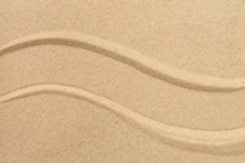 A close-up of two parallel, wavy lines drawn in light brown sand.