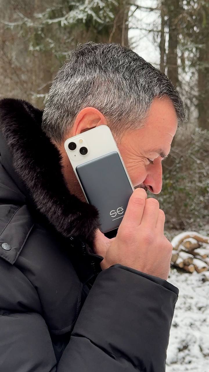 Man in winter coat holding a smartphone to his ear outdoors.