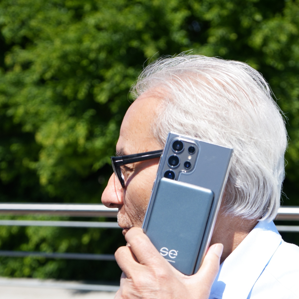 Person with white hair holding a smartphone to their ear outdoors.