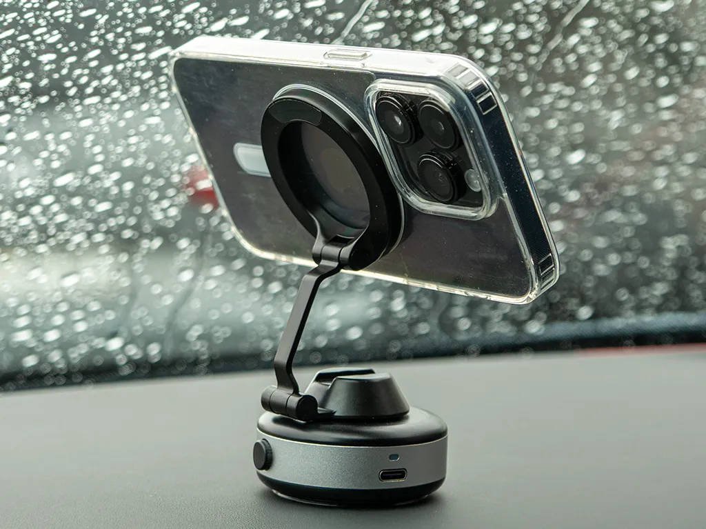 Smartphone mounted on a dashboard holder with raindrops on the window in the background.