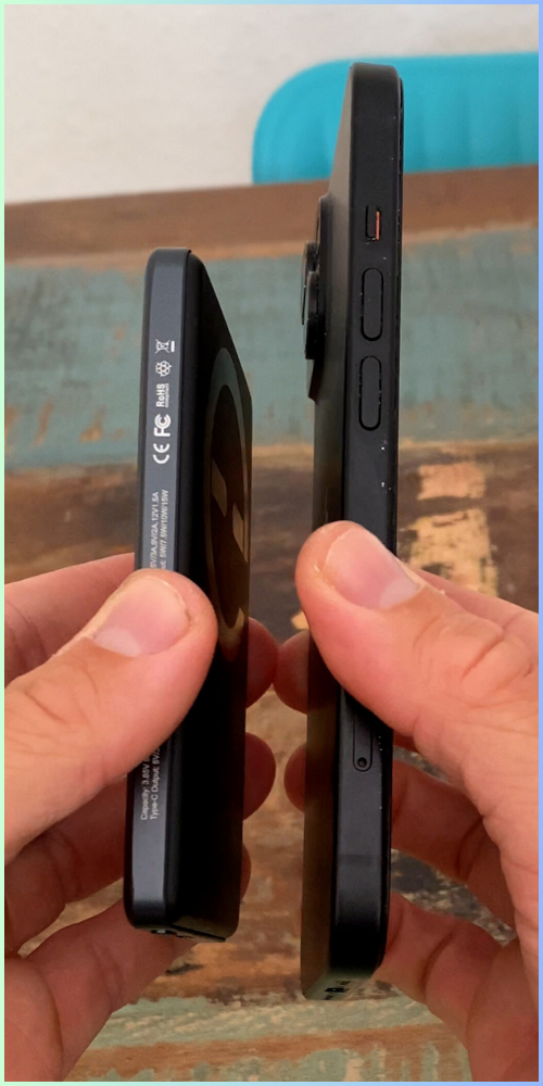 Two hands holding a smartphone and a small rectangular device side by side.
