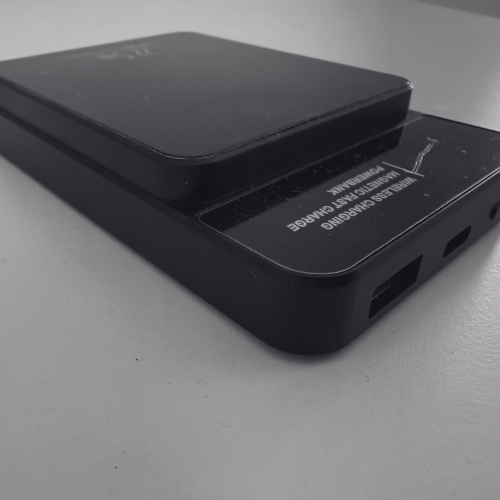 Black wireless charging power bank on a white surface.