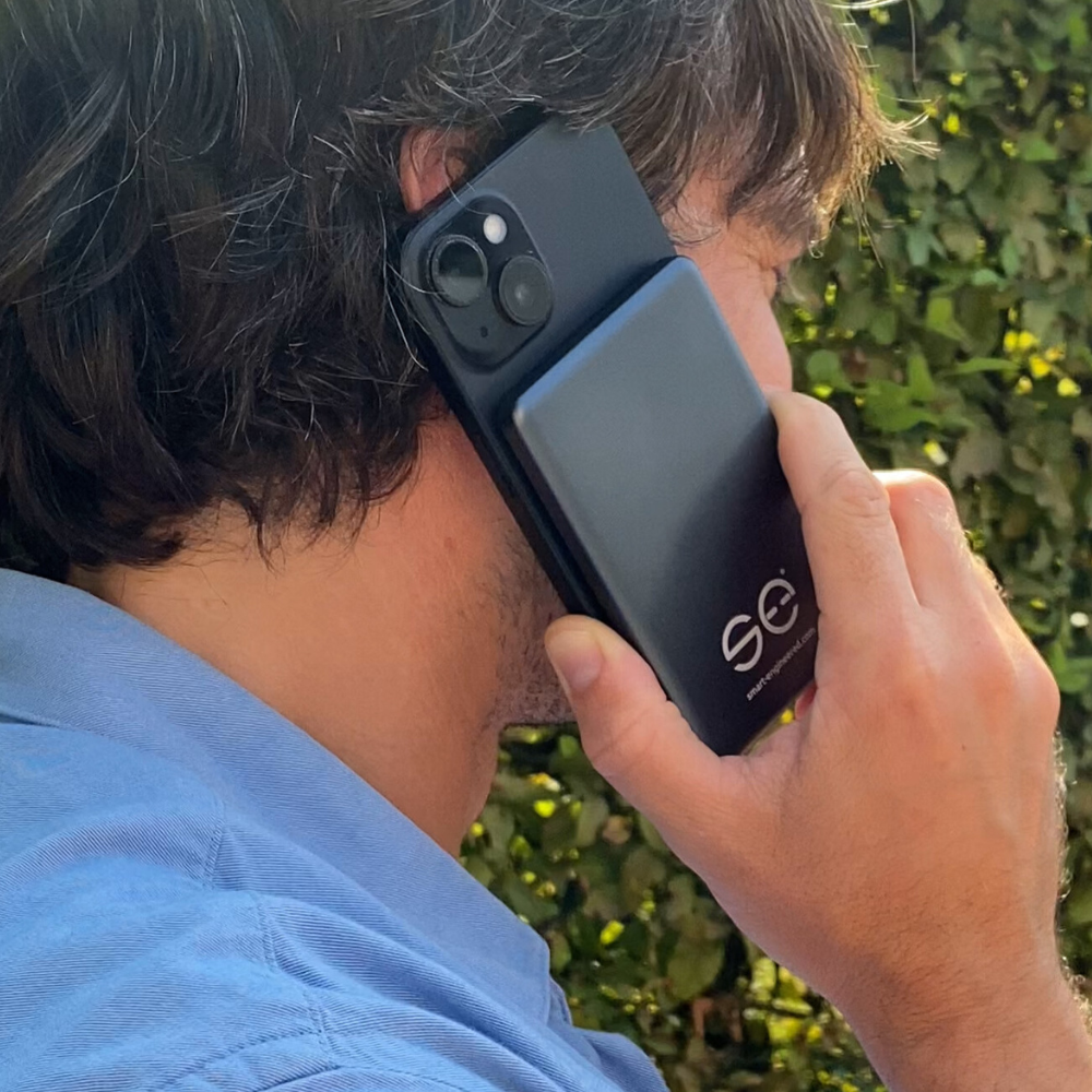 Person holding a smartphone with a black case to their ear.