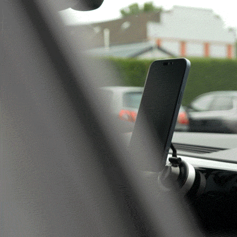 Smartphone on a car dashboard mount with blurred background.